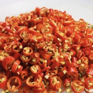 Thinly sliced red chilli peppers with visible seeds are displayed on a white surface, freshly prepared using the DX-50T Multi-Slicer (Chilli Padi Model).